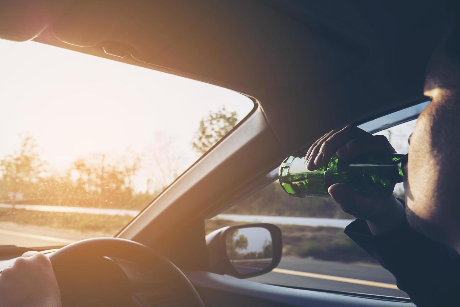 Man drinking beer while driving a car photo