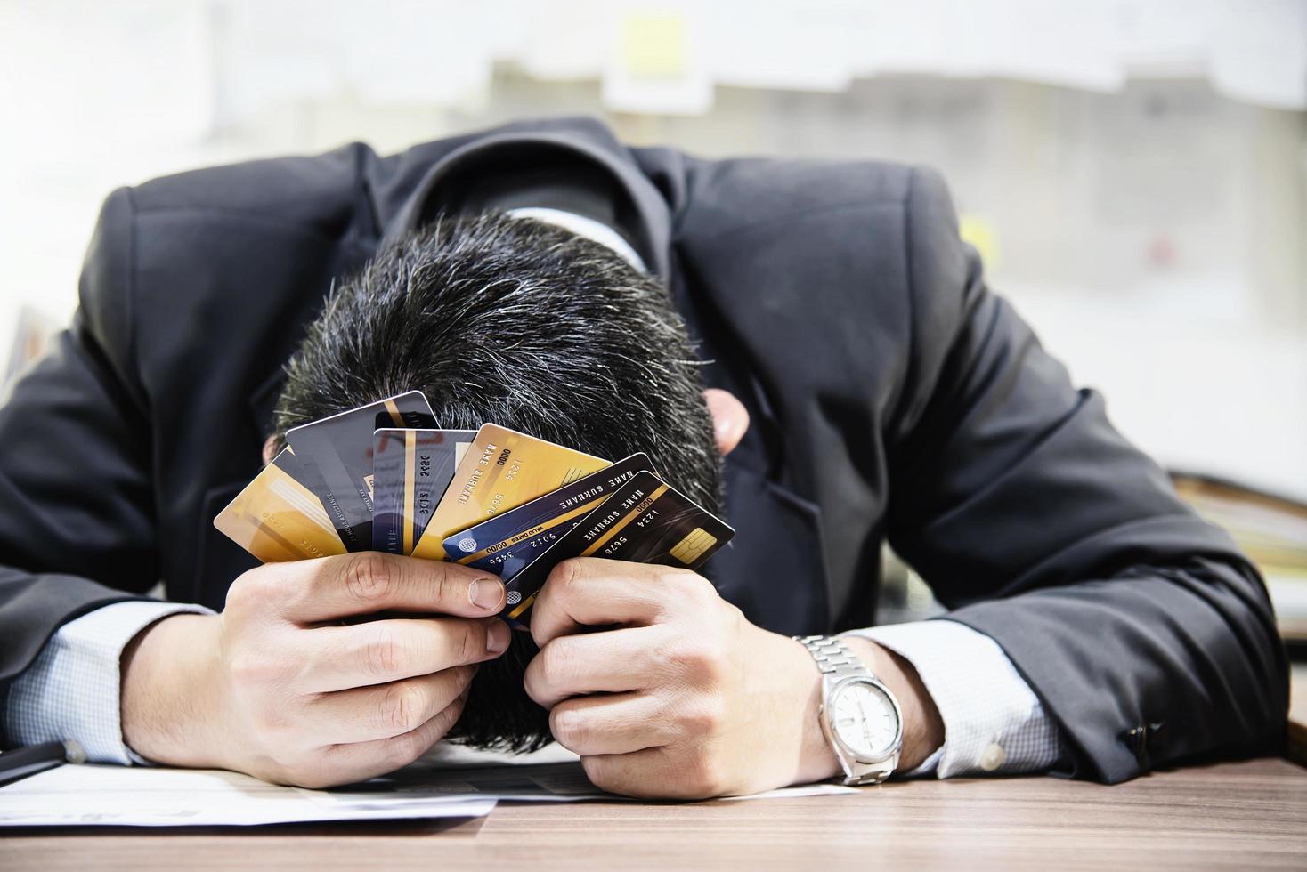 Businessman holding credit cards thinking seriously about payment loan problem - people with personal financial crisis concept photo