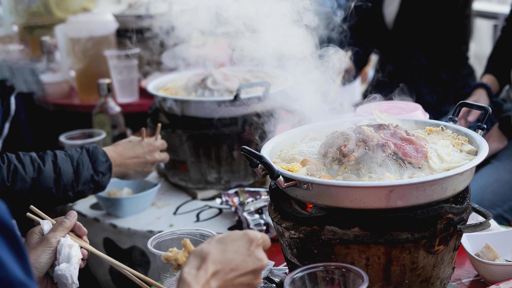 gente comiendo cerdo a la parrilla, llamado moo kratha, comida famosa para el clima frío en la naturaleza montañosa, moncham, chiang mai tailandia - famoso lugar turístico foto