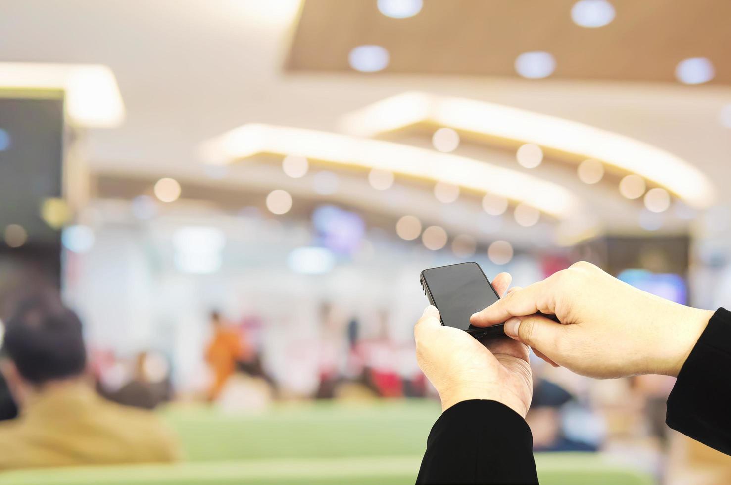 A man is using telephone over colorful blurred bokeh light in office and people background photo