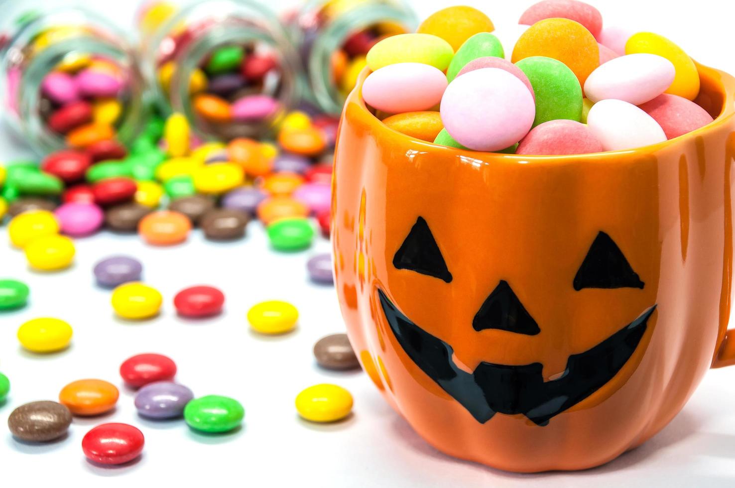 Halloween pumpkin face buckets with colorful candy photo