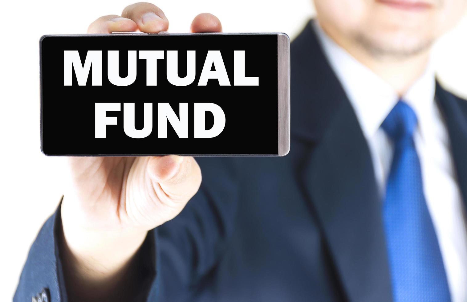 MUTUAL FUND word on mobile phone screen in blurred young businessman hand over white background, business concept photo