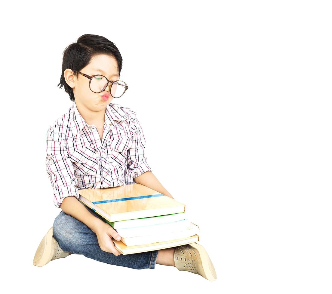 7 years old Asian boy is feeling Bored with a pile of book isolated over white. photo