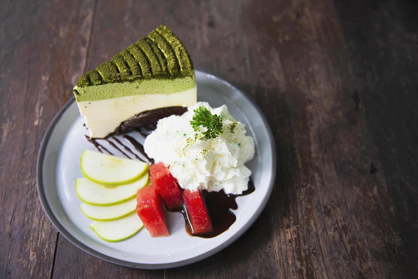 Colorful green tea favor cake with well decorated fruit pieces and whipped cream in white plate - cake recipe menu concept photo