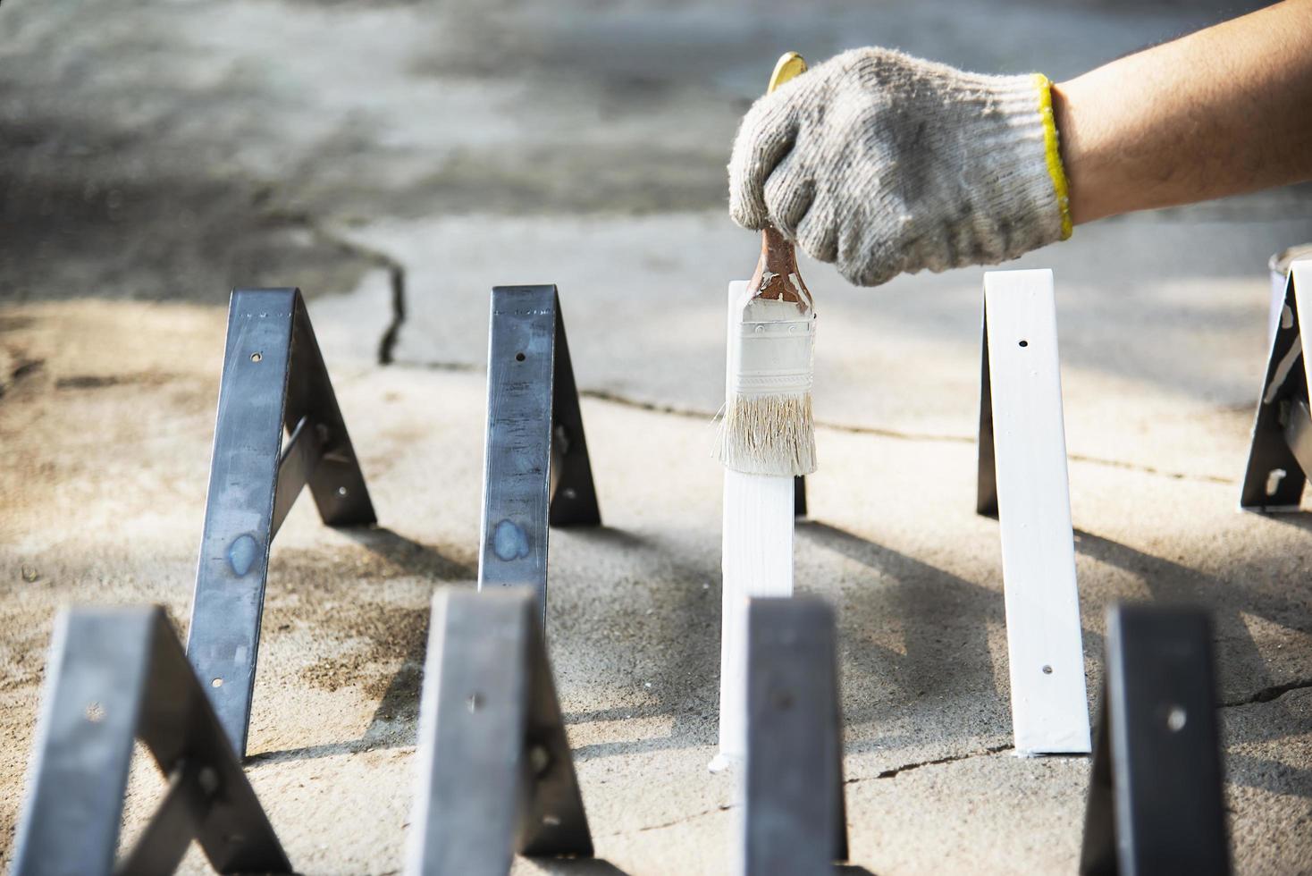 Man is coating white color for steel furniture part - painter at work concept photo