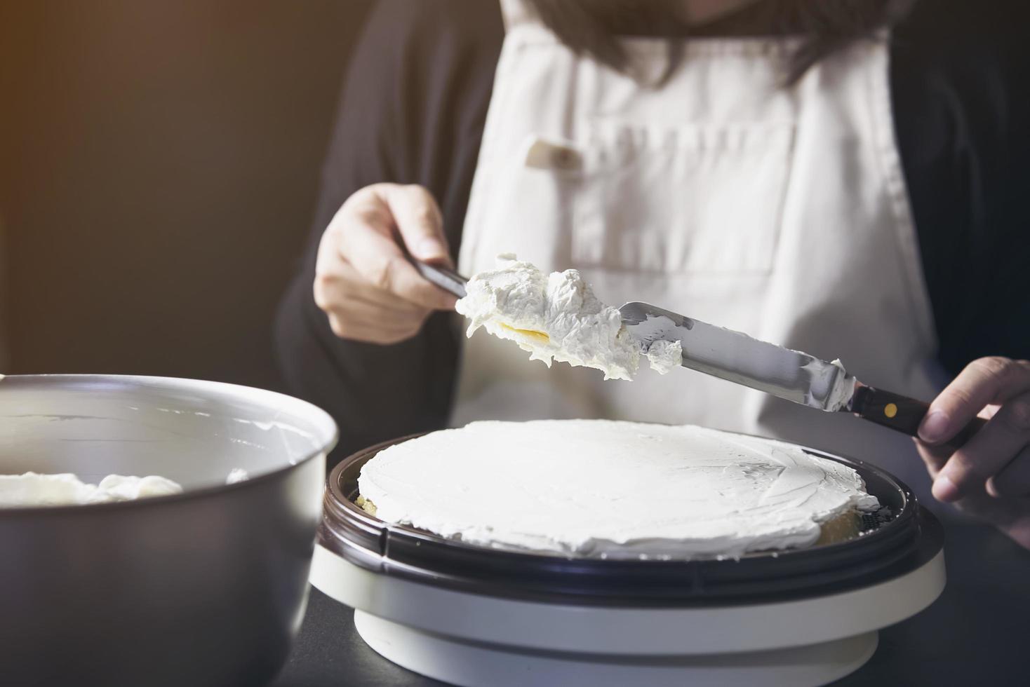 Lady making cake putting cream using spatula - homemade bakery cooking concept photo