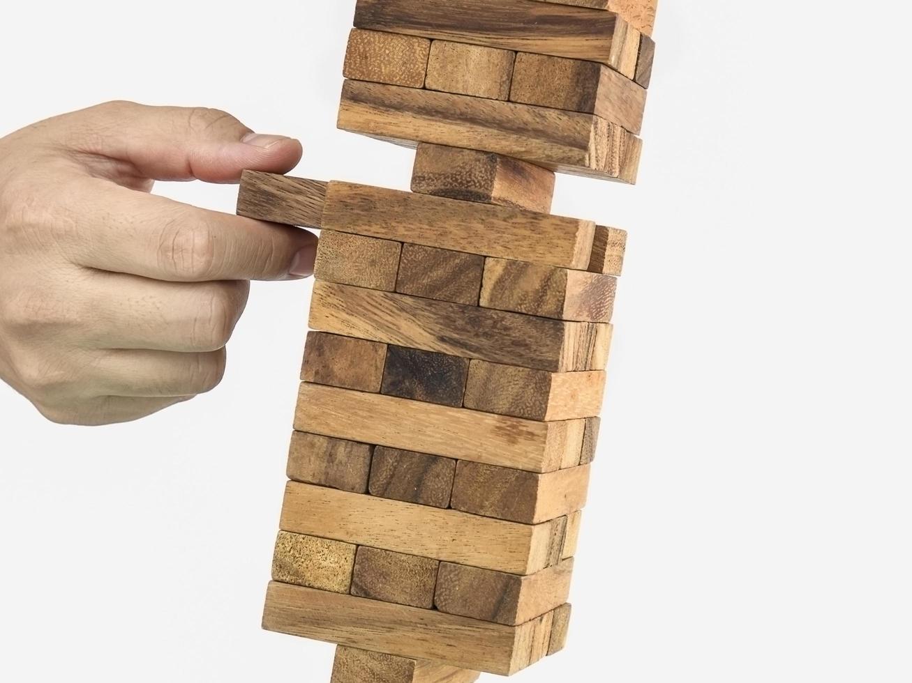 torre de bloques de madera inclinada juego jenga con mano, concepto de riesgo foto