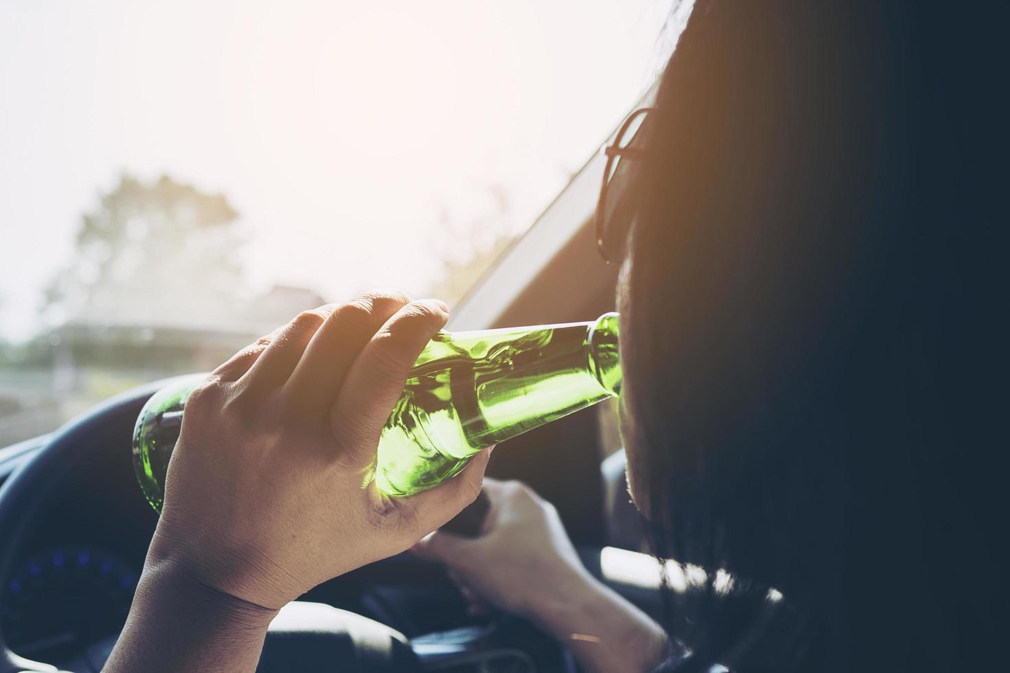 Woman drinking beer while driving a car photo