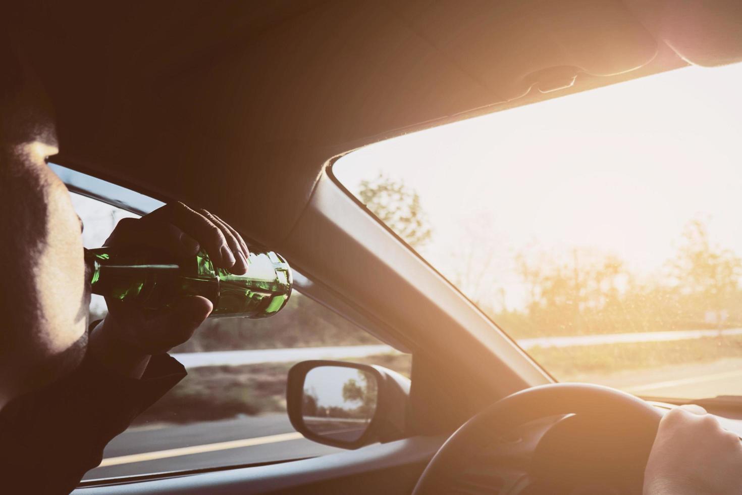 Man drinking beer while driving a car photo