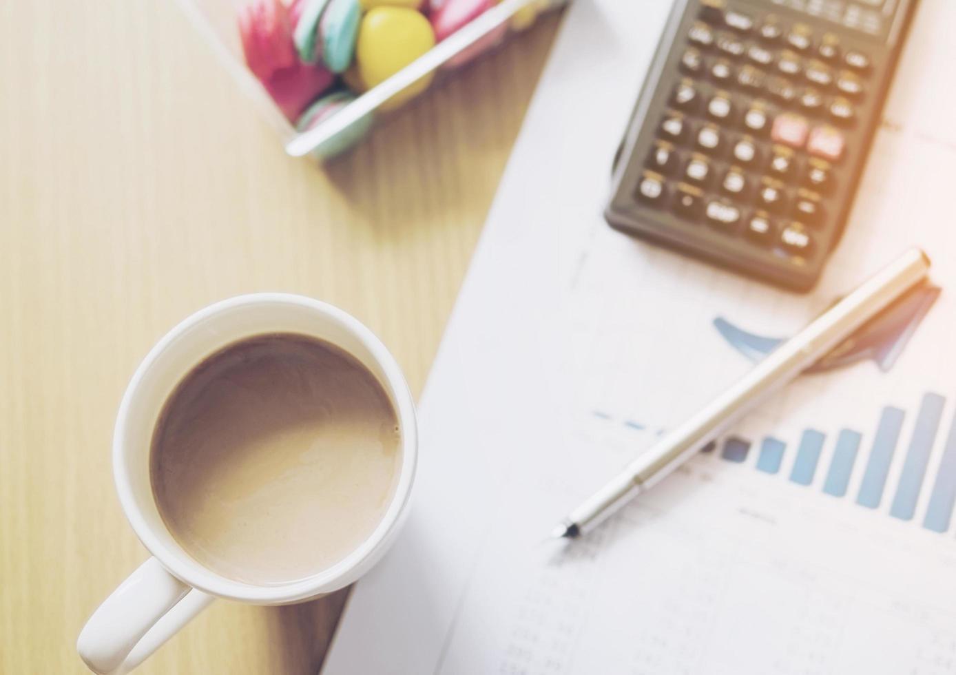 Vintage style photo of business financial working concept, pen an calculator on growth bar graph with coffee cup and macaroon background selective focused