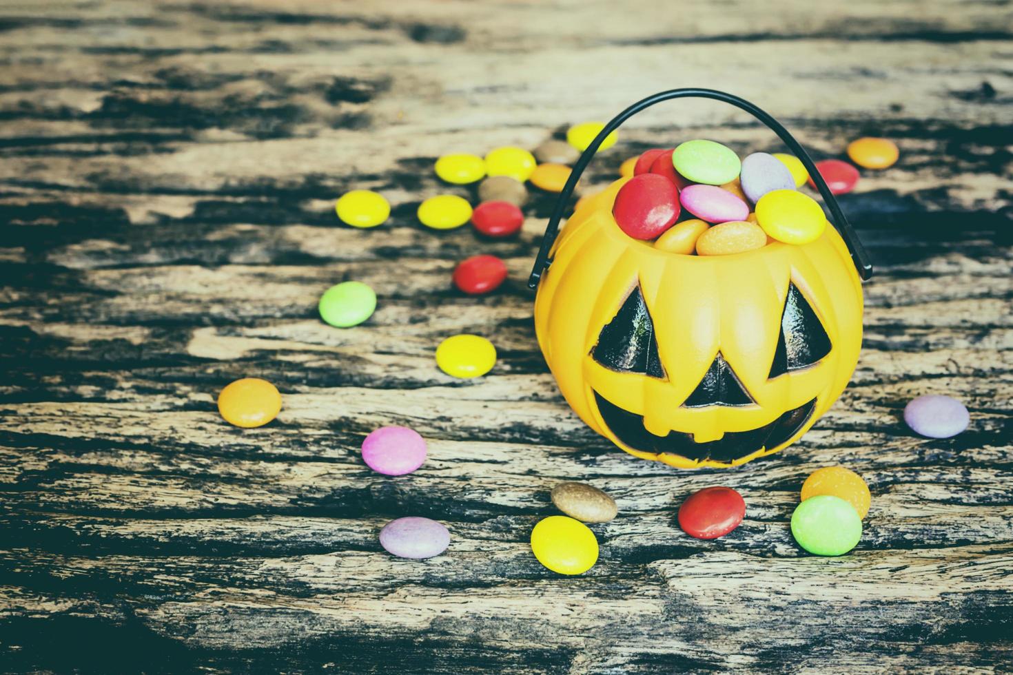 Halloween pumpkin face buckets with colorful candy inside on old wooden texture photo