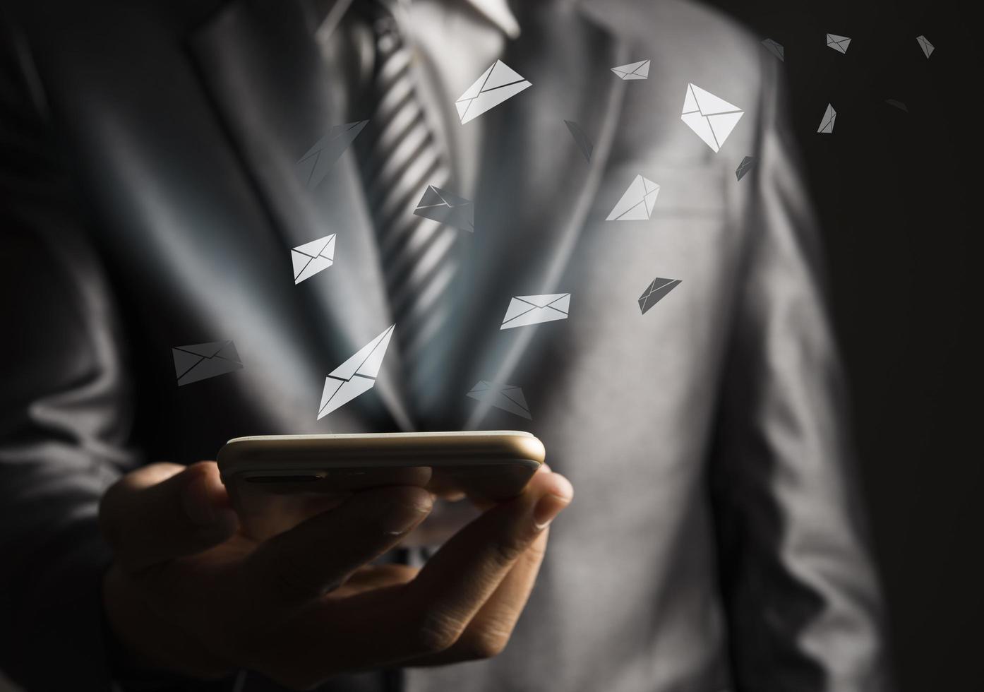 Business man using mobile phone with flying envelope photo