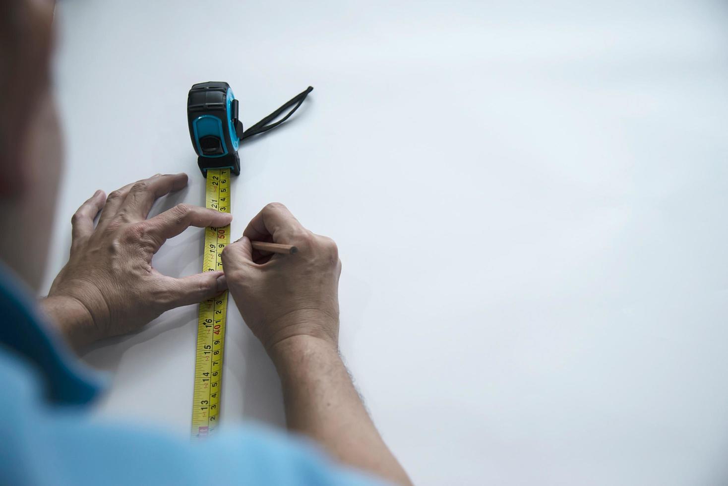 hombre que usa la herramienta de mano de medida haciendo trabajos de corte de papel tapiz en el sitio de construcción de viviendas, personas con el concepto de objeto de herramienta de mano foto