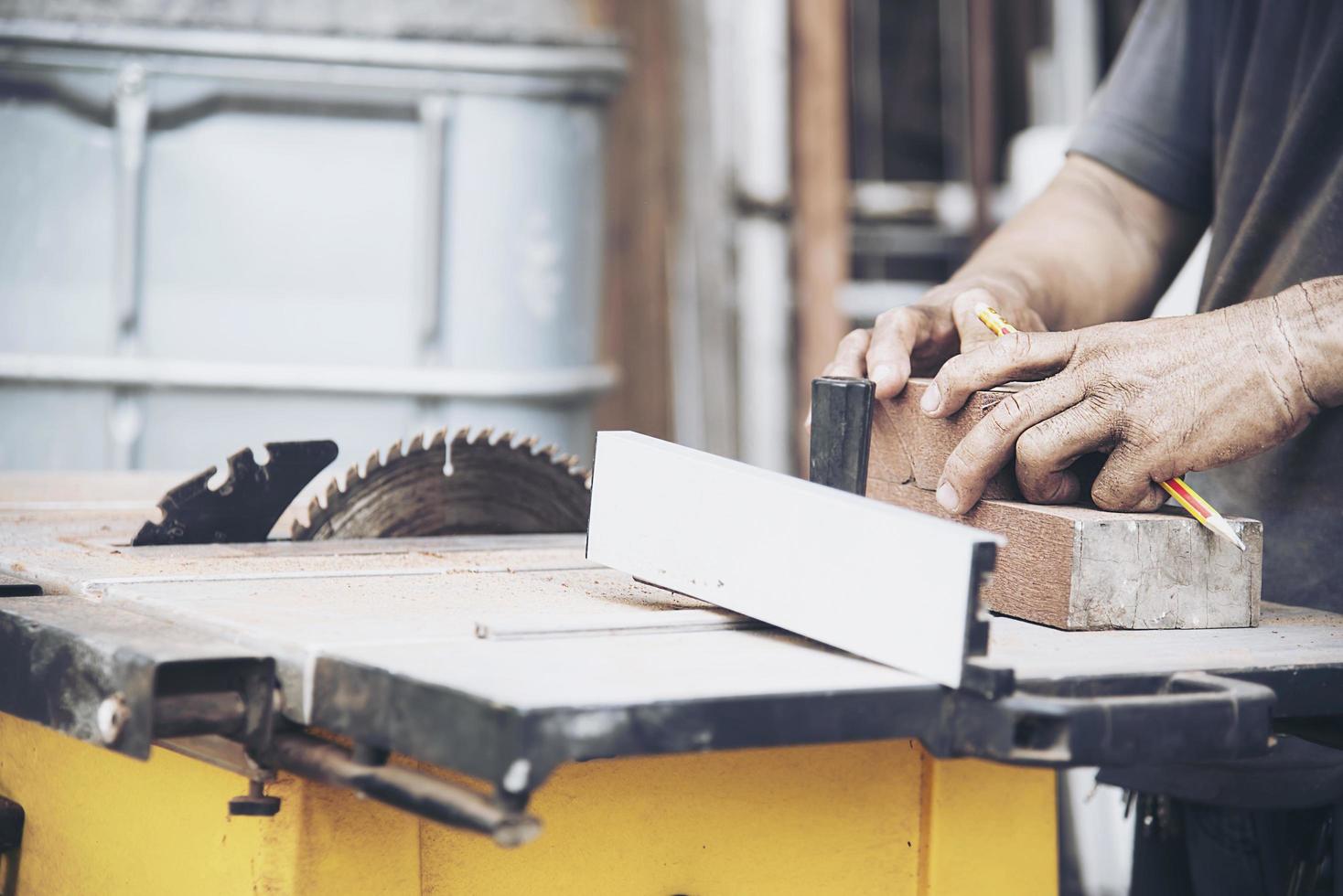Carpenter man is working with circular saw machine table tool for cutting his wooden piece work photo