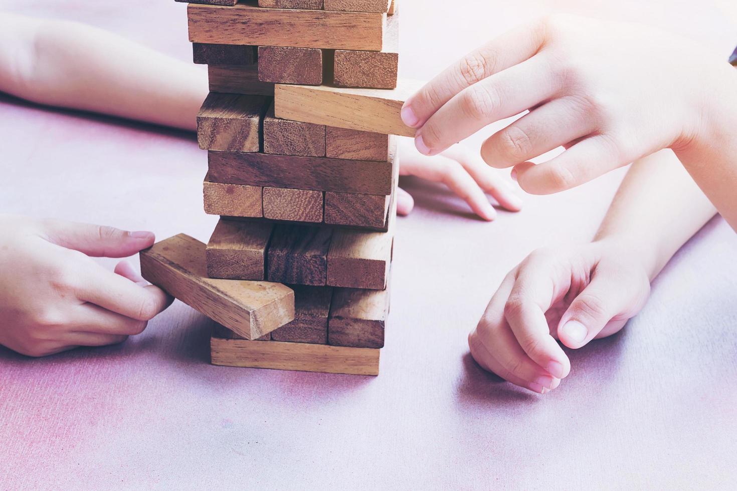 los niños de cerca están jugando al juego de la torre de bloques de madera foto