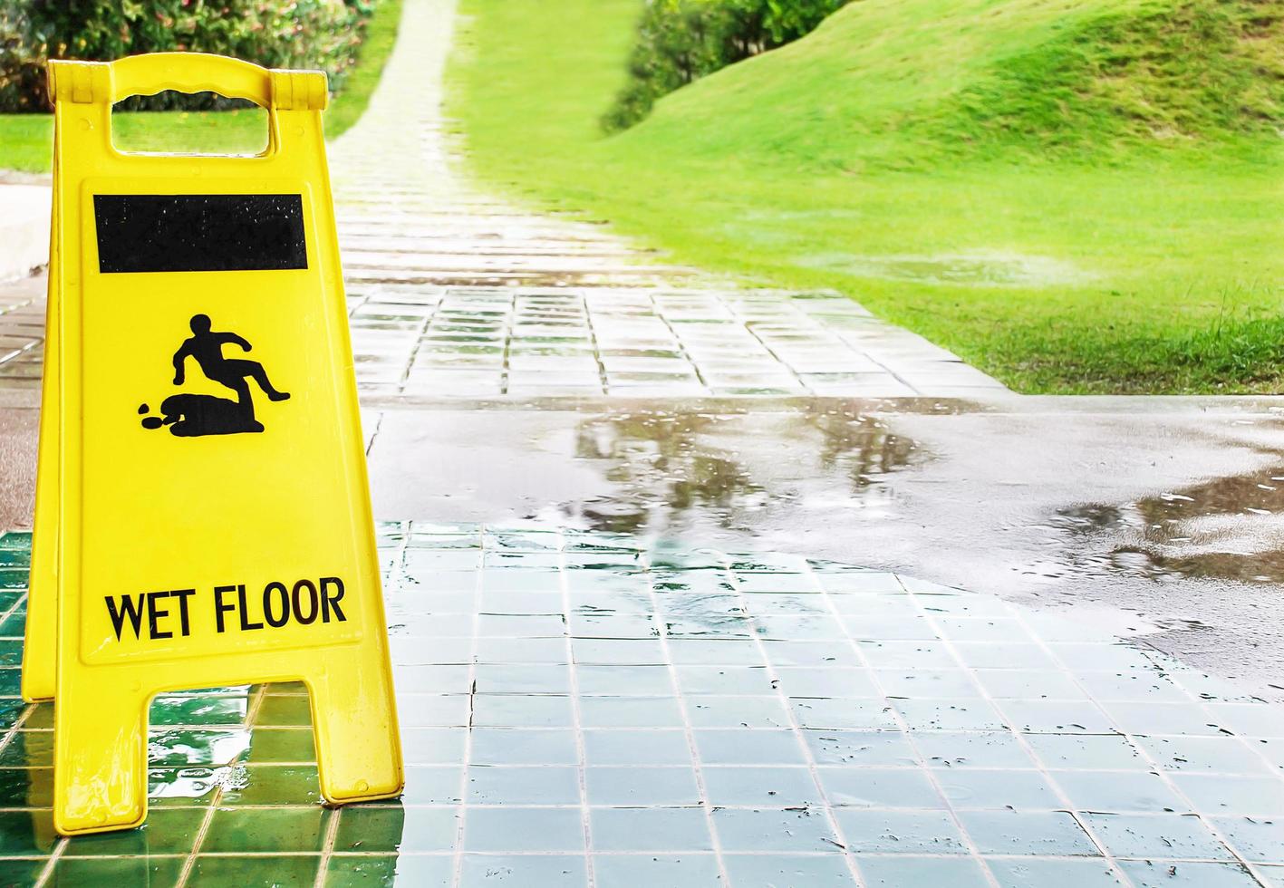 Wet floor caution sign with rain drop on the green tiles floor photo