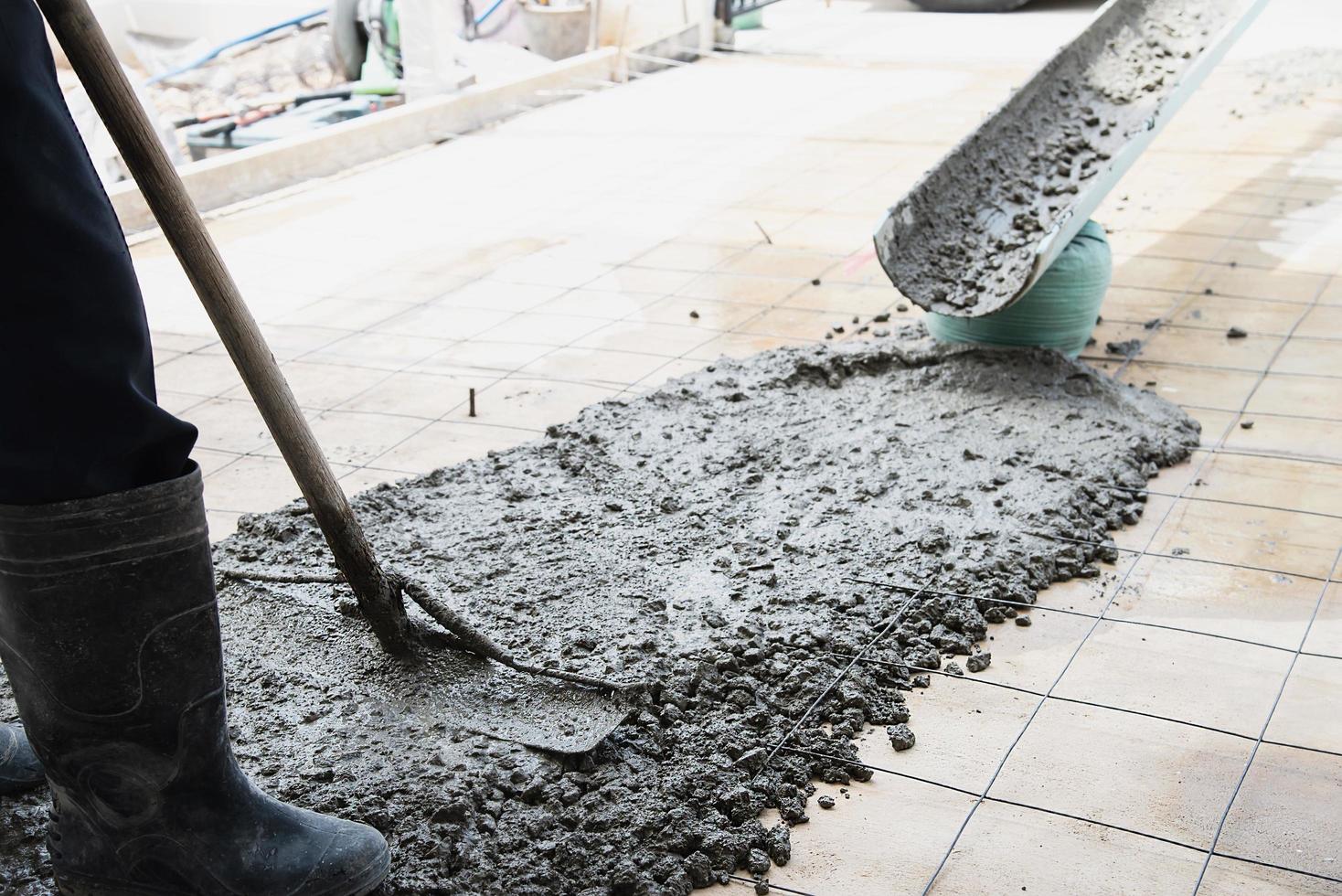 Workman doing floor concrete pouring job in construction site photo