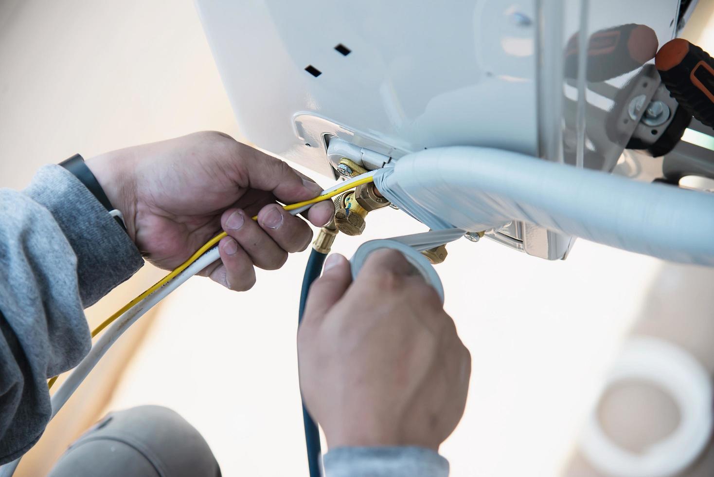 Man is installing wall compressor of air conditioner during hot season photo