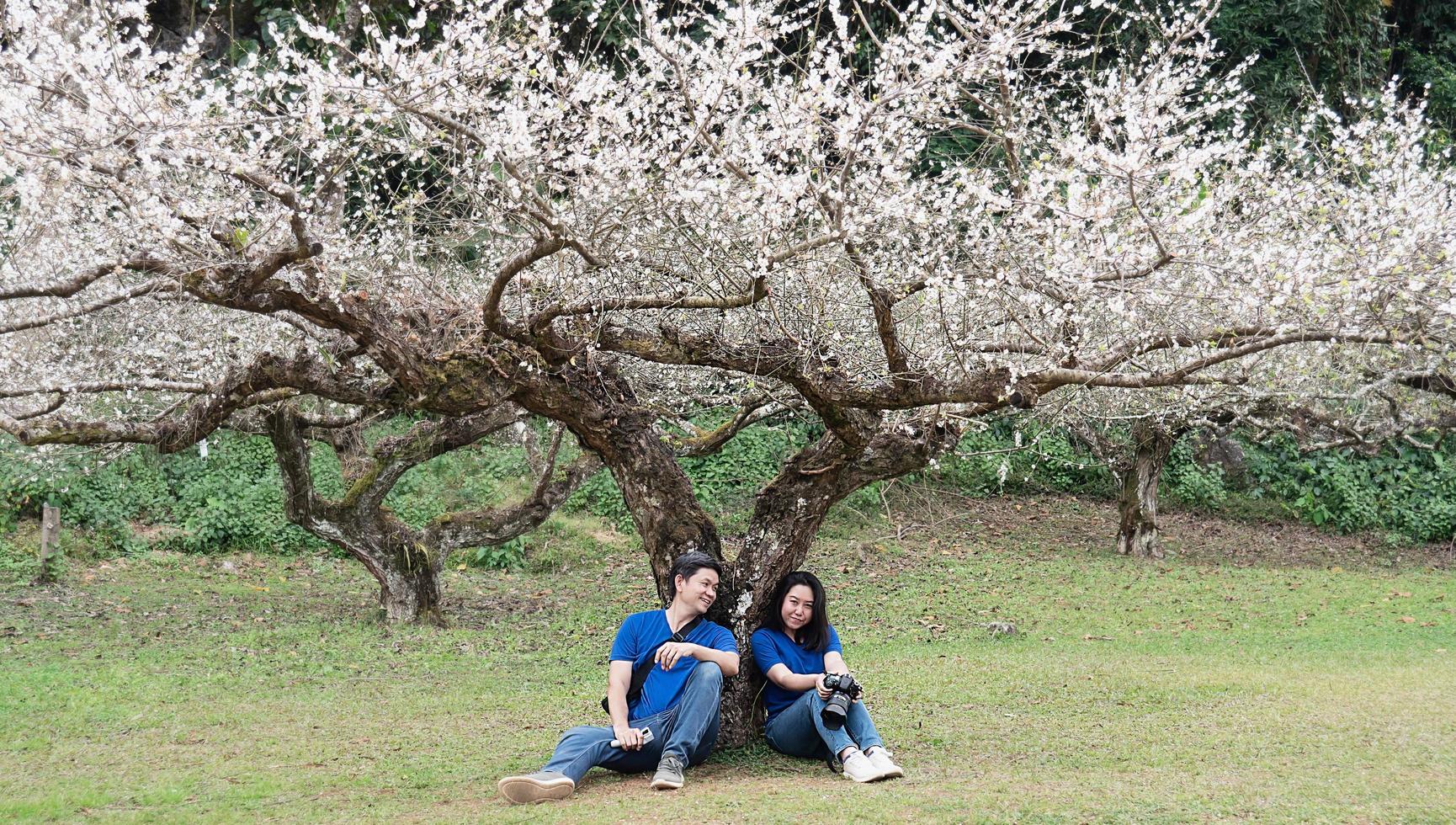 pareja asiática feliz tomando fotos en el hermoso jardín de melocotón de la naturaleza en doi ang khang, chiangmai tailandia