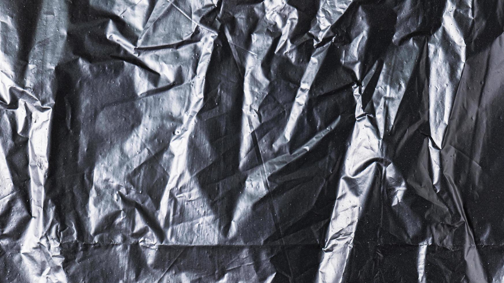 The background image of black plastic trash bags has creases creating a rough texture with light and shadow. photo