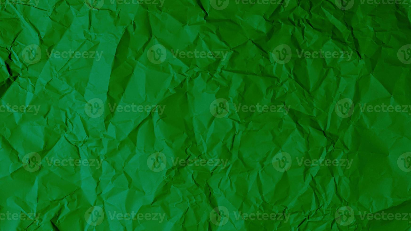 The green paper background is wrinkled, creating a rough texture with light and shadow. photo