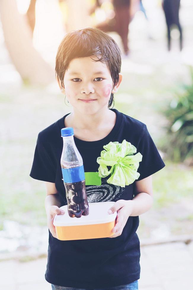 Asian lovely kid showing his lunch box set at school photo