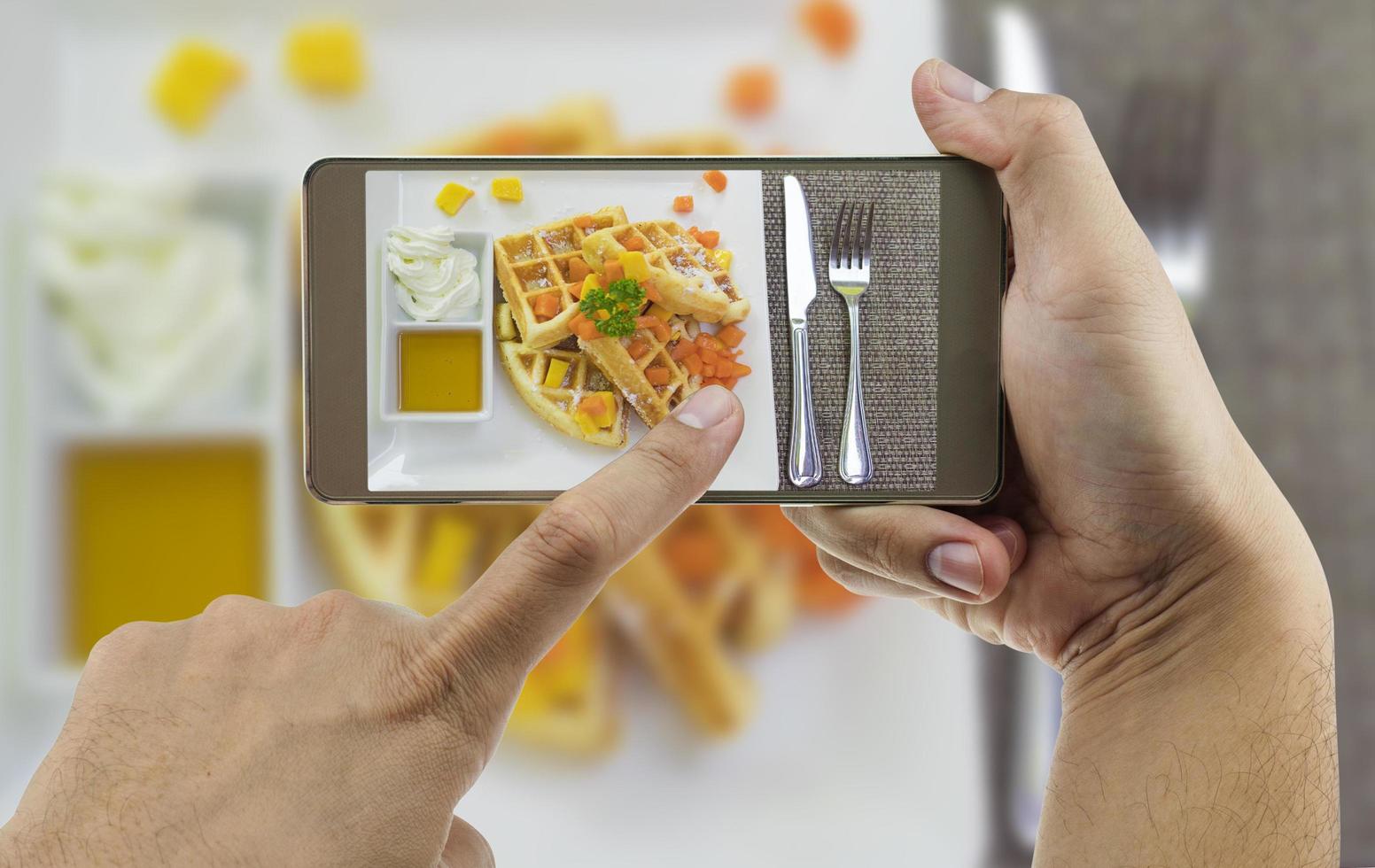 People using mobile phone taking photo of colorful waffles on white plate