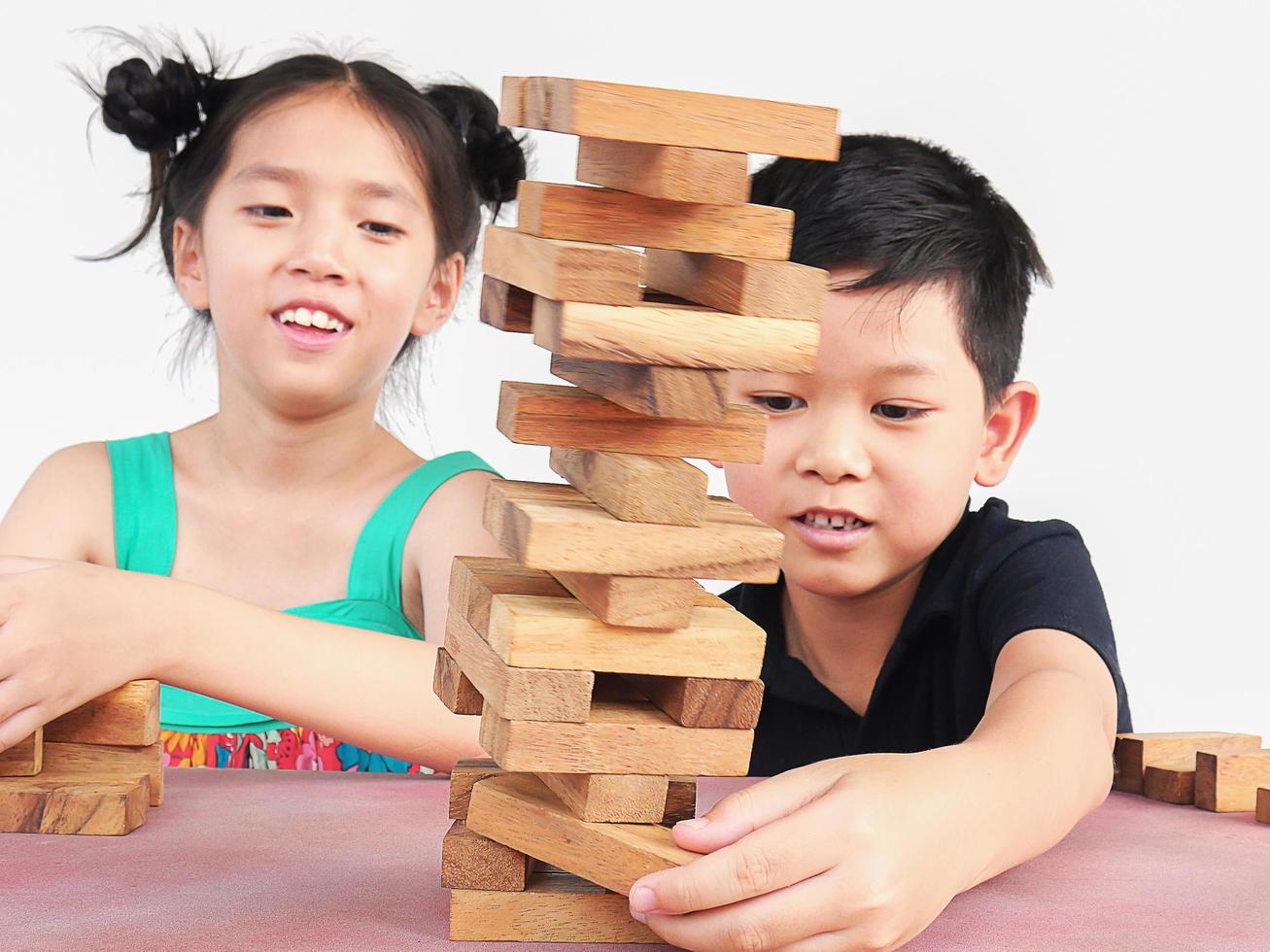 Children are playing a wood blocks tower game for practicing their physical and mental skill. Photo focus on hands Boy