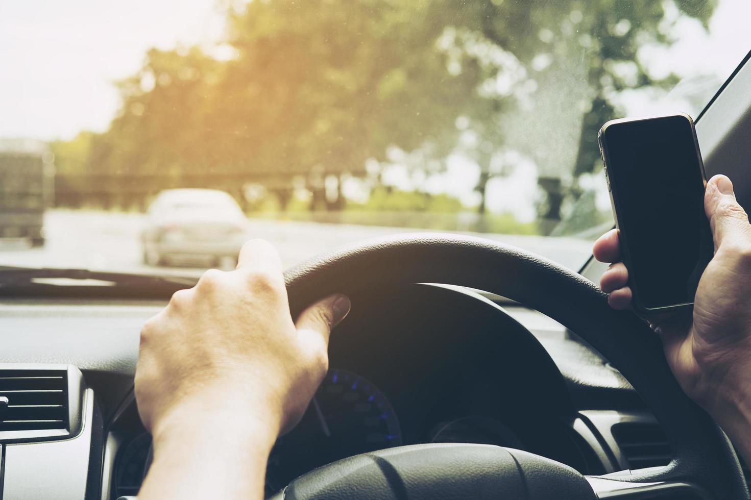 Close up of a man driving car dangerously while using mobile phone photo