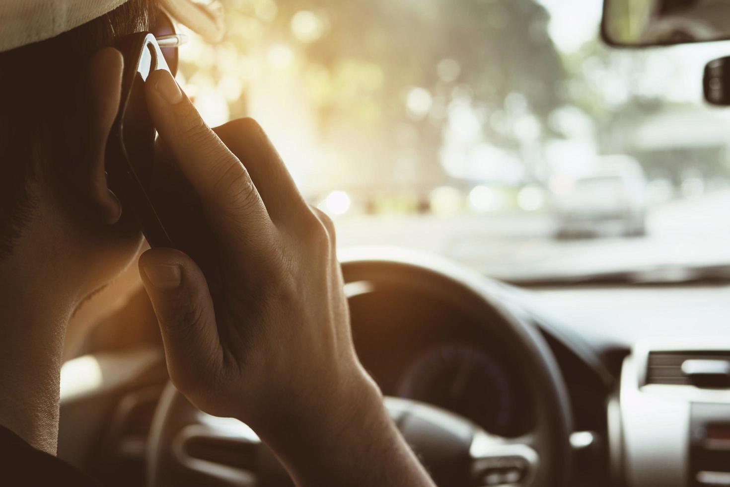 Close up of a man driving car dangerously while using mobile phone photo
