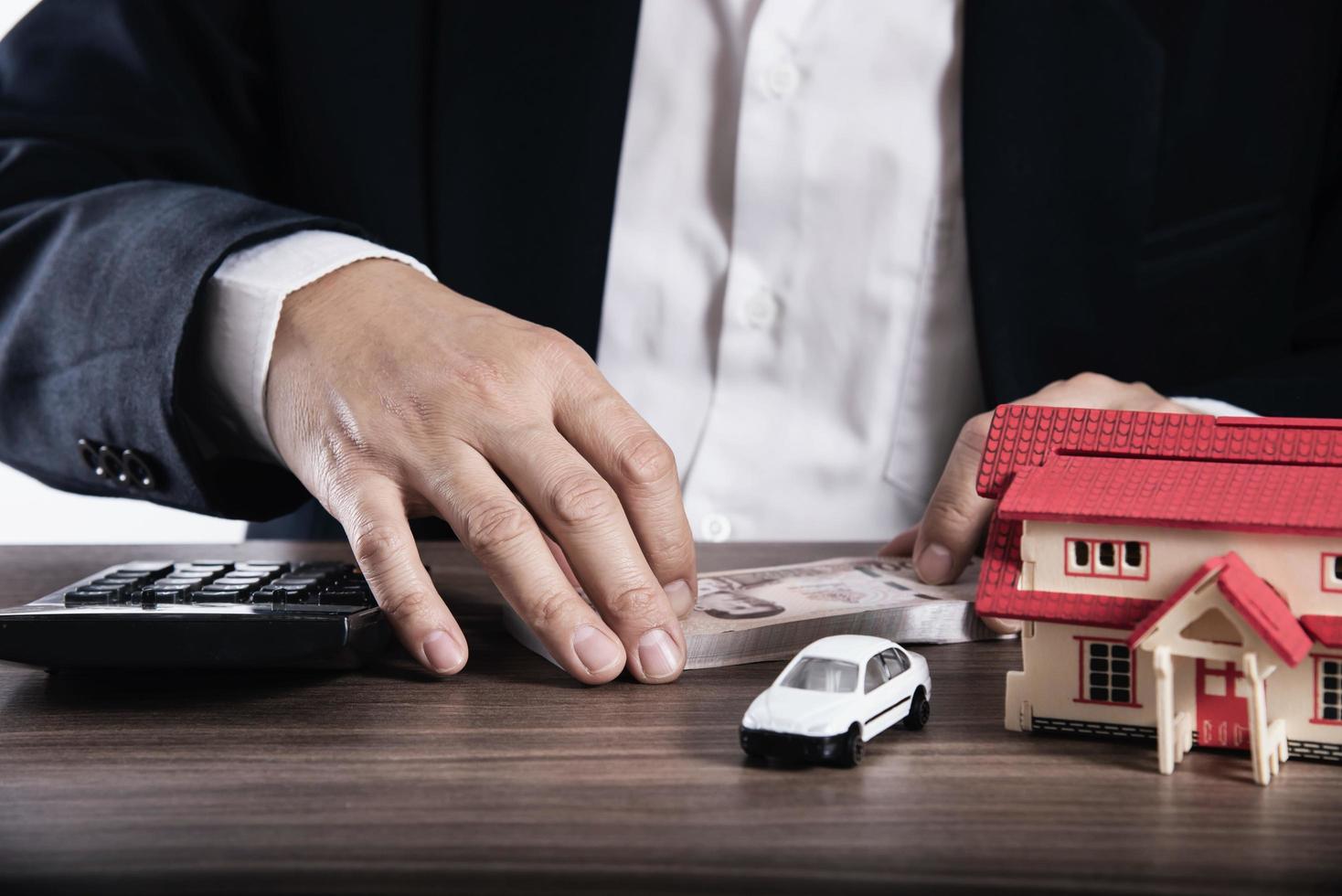 el hombre de negocios está usando una calculadora pensando en el dinero para el pago de la casa y el automóvil - personas con concepto de seguro financiero de bienes raíces foto