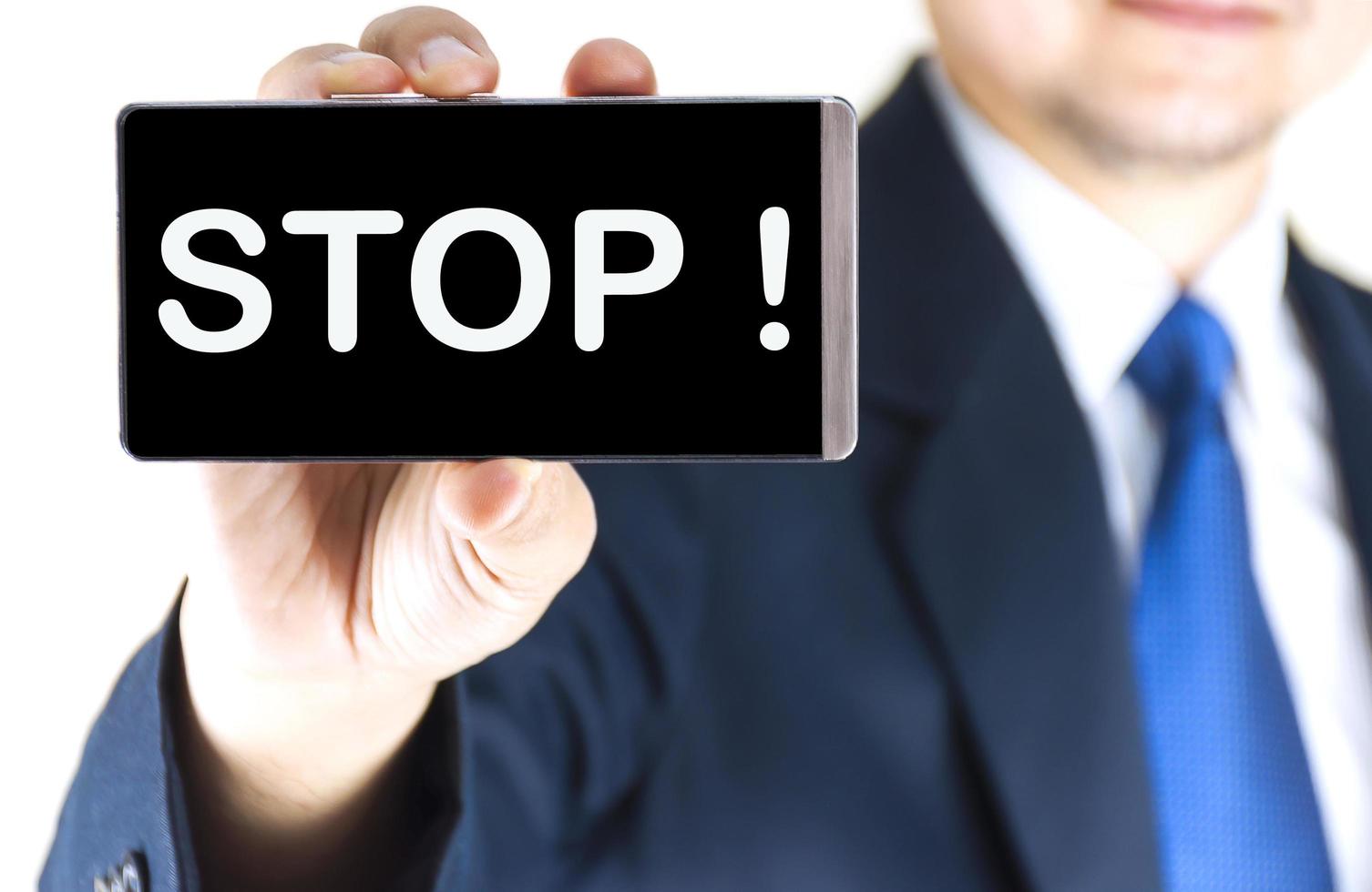 STOP , word on mobile phone screen in blurred young businessman hand over white background, business concept photo