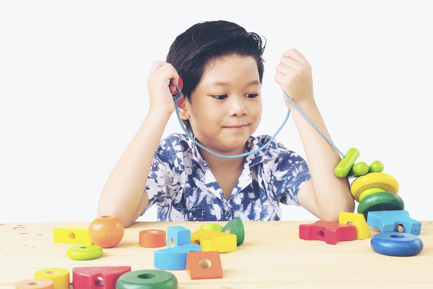 Lovely asian boy is play colorful wood block toy photo