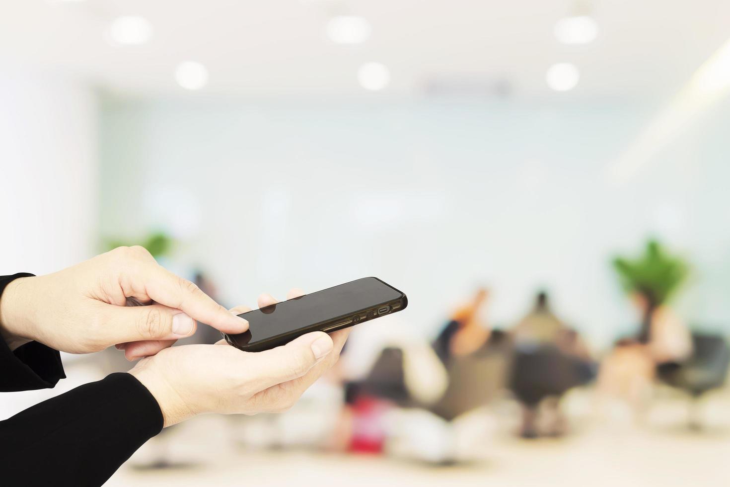 A man is using telephone over blurred bokeh light in office and people background photo