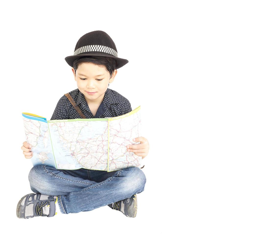 7 years old Asian traveler boy is happily sitting and looking at a map. photo