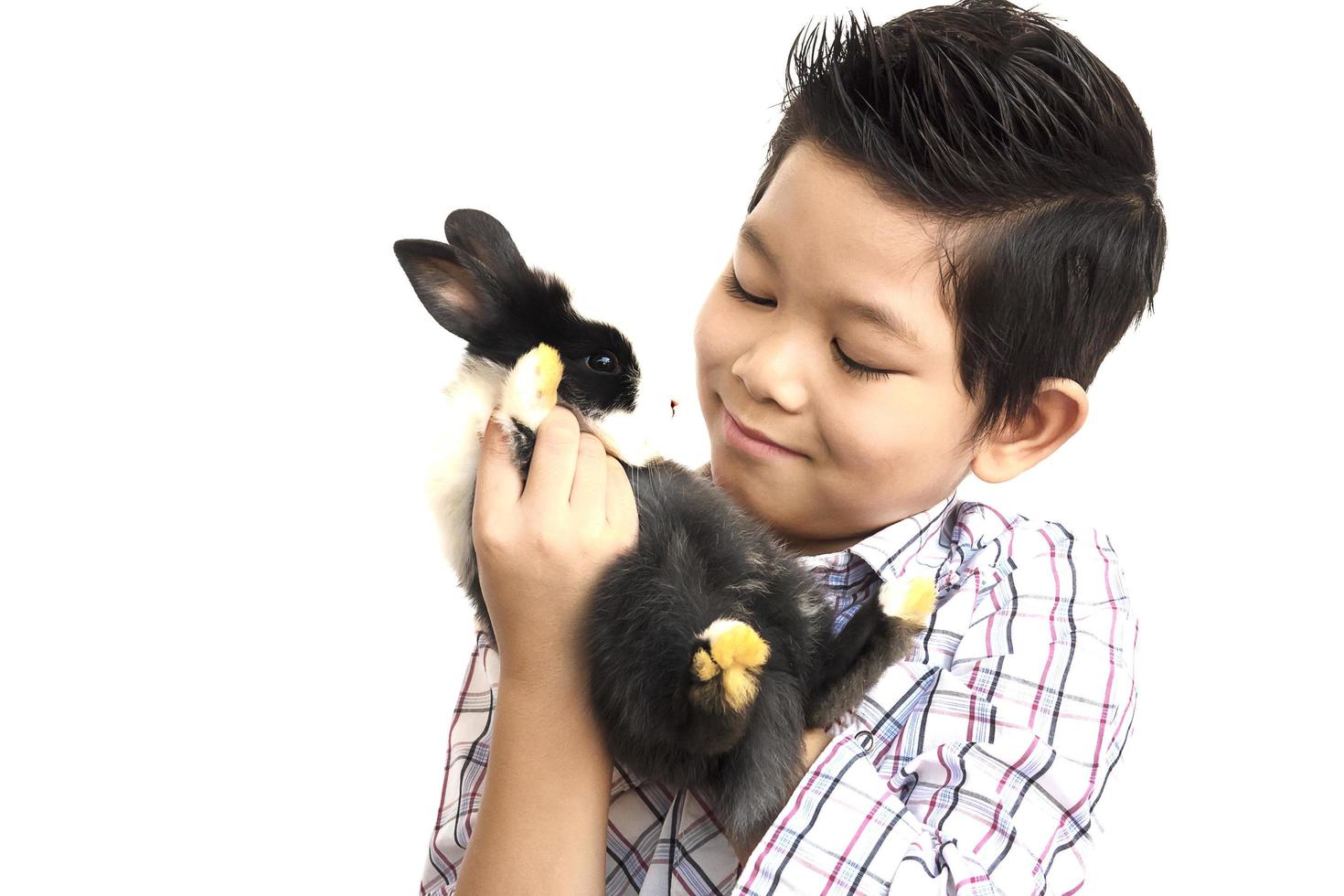 Asian kid playing with lovely baby rabbit isolated over white photo