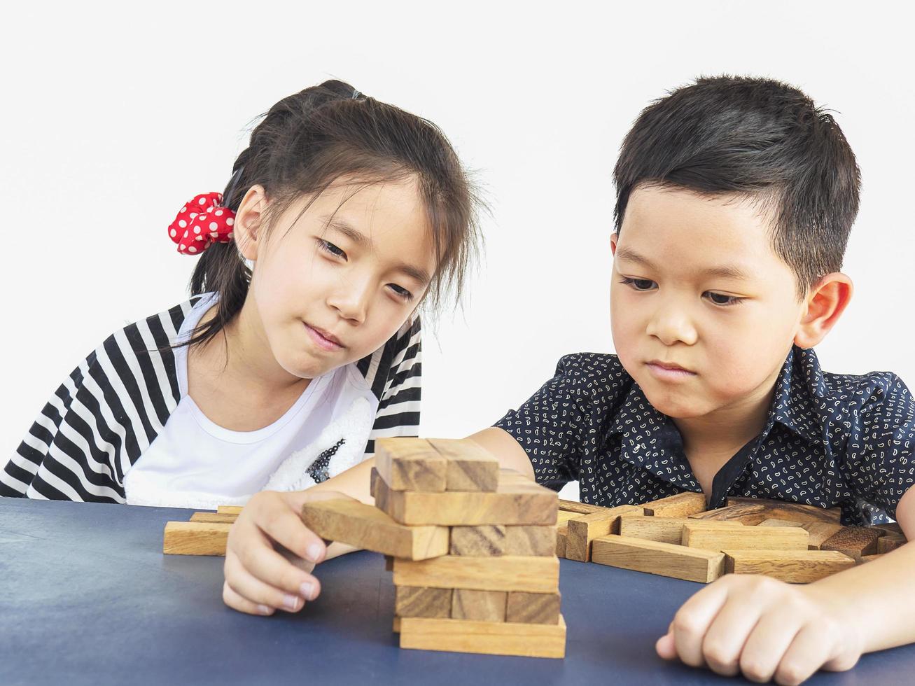 Children is playing jenga, a wood blocks tower game for practicing their physical and mental skill photo