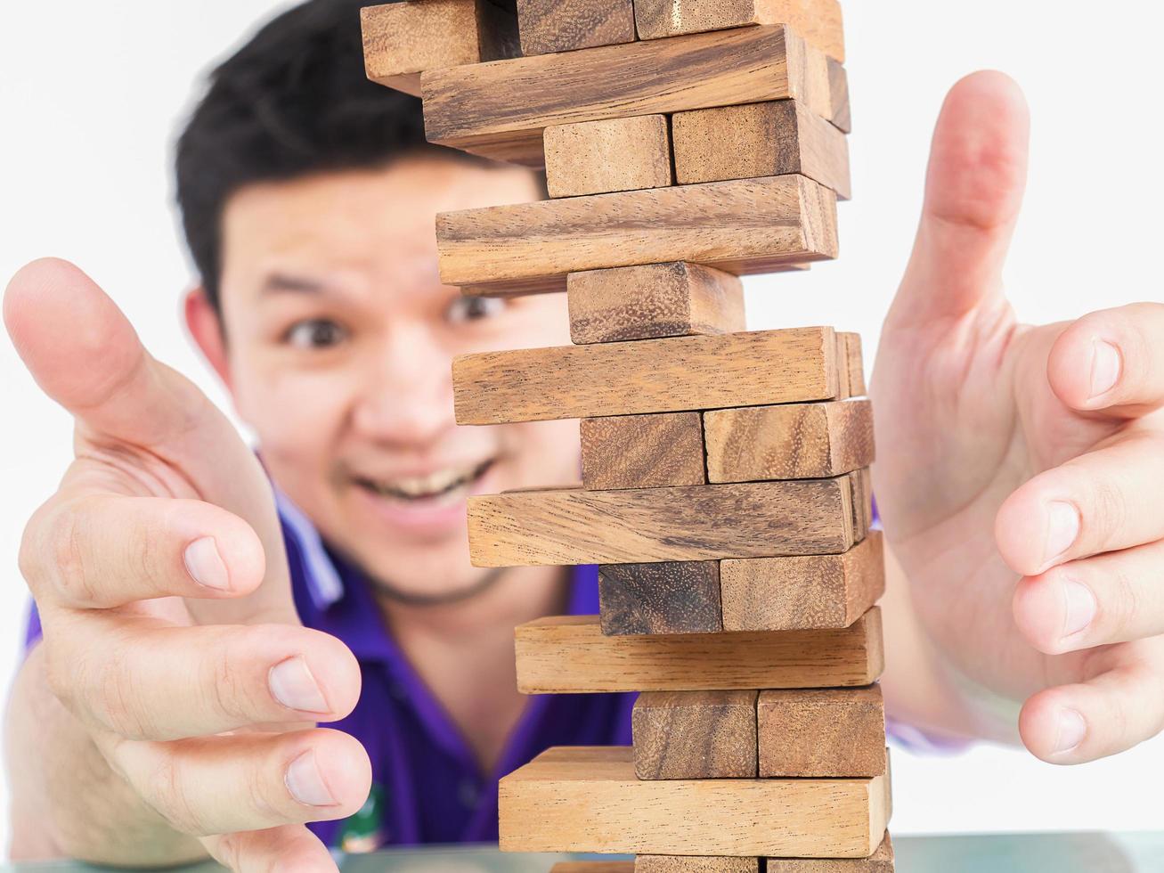 Asian guy is playing jenga, a wood blocks tower game for practicing physical and mental skill photo