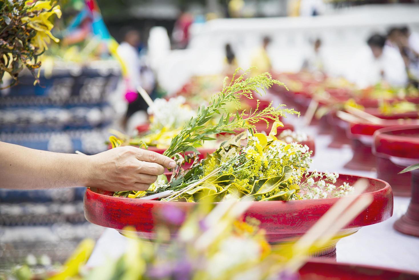 Asian man holding fresh yellow flowers for participation local traditional Buddhist  ceremony - people with religion relationship concept photo