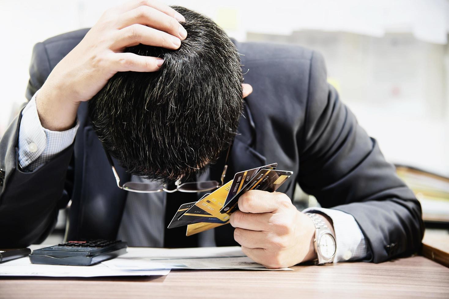 Businessman holding credit cards thinking seriously about payment loan problem - people with personal financial crisis concept photo