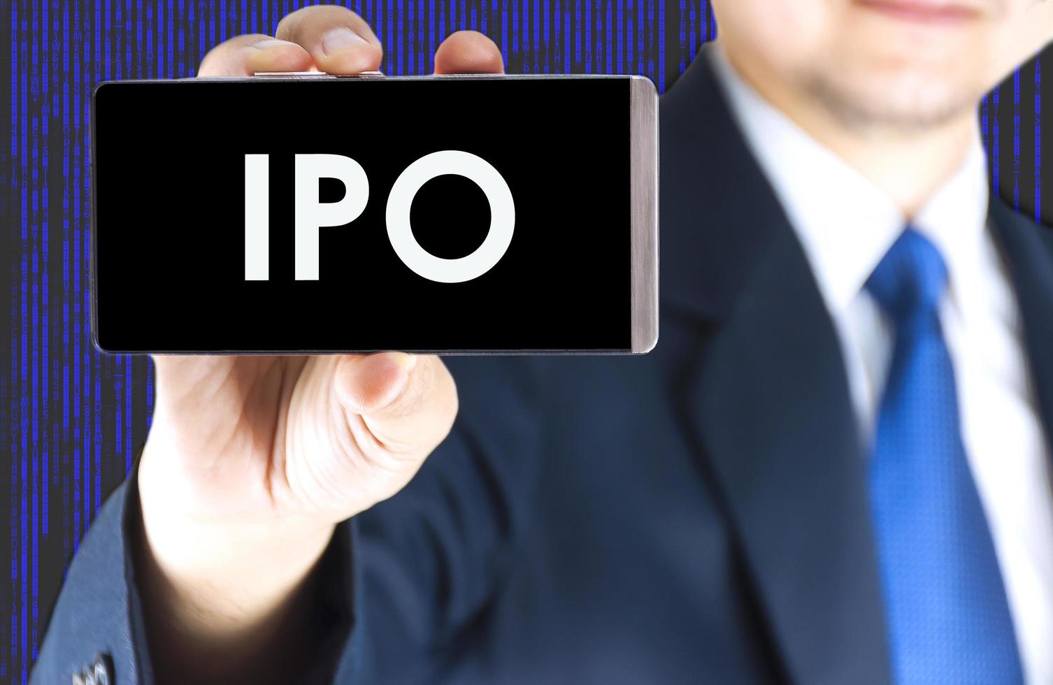 ipo, oferta pública inicial, palabra en la pantalla del teléfono móvil en la mano de un joven empresario borroso y antecedentes de tecnología digital, concepto de negocio foto