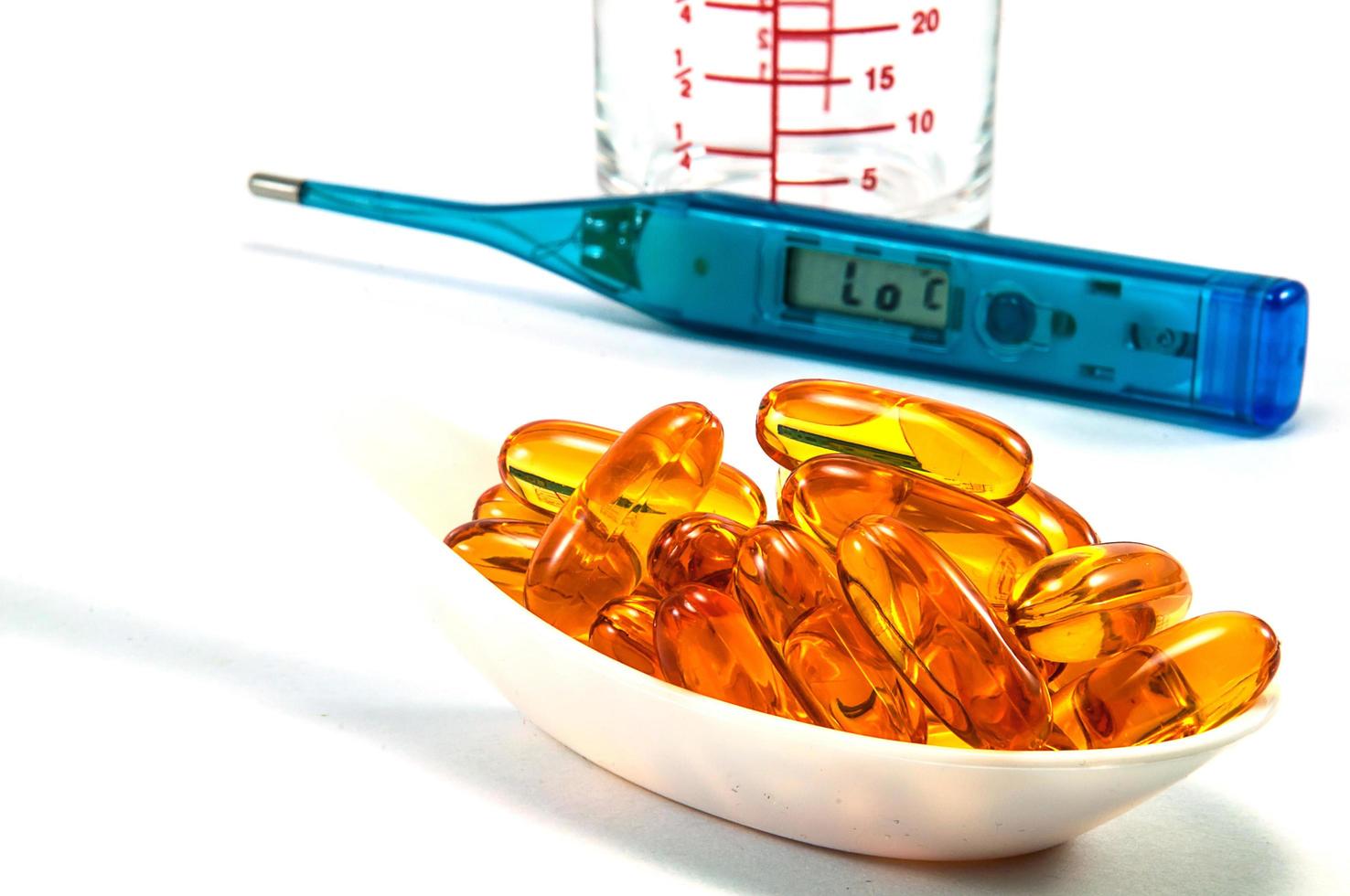 Fish oil with thermometer and glass on white background photo