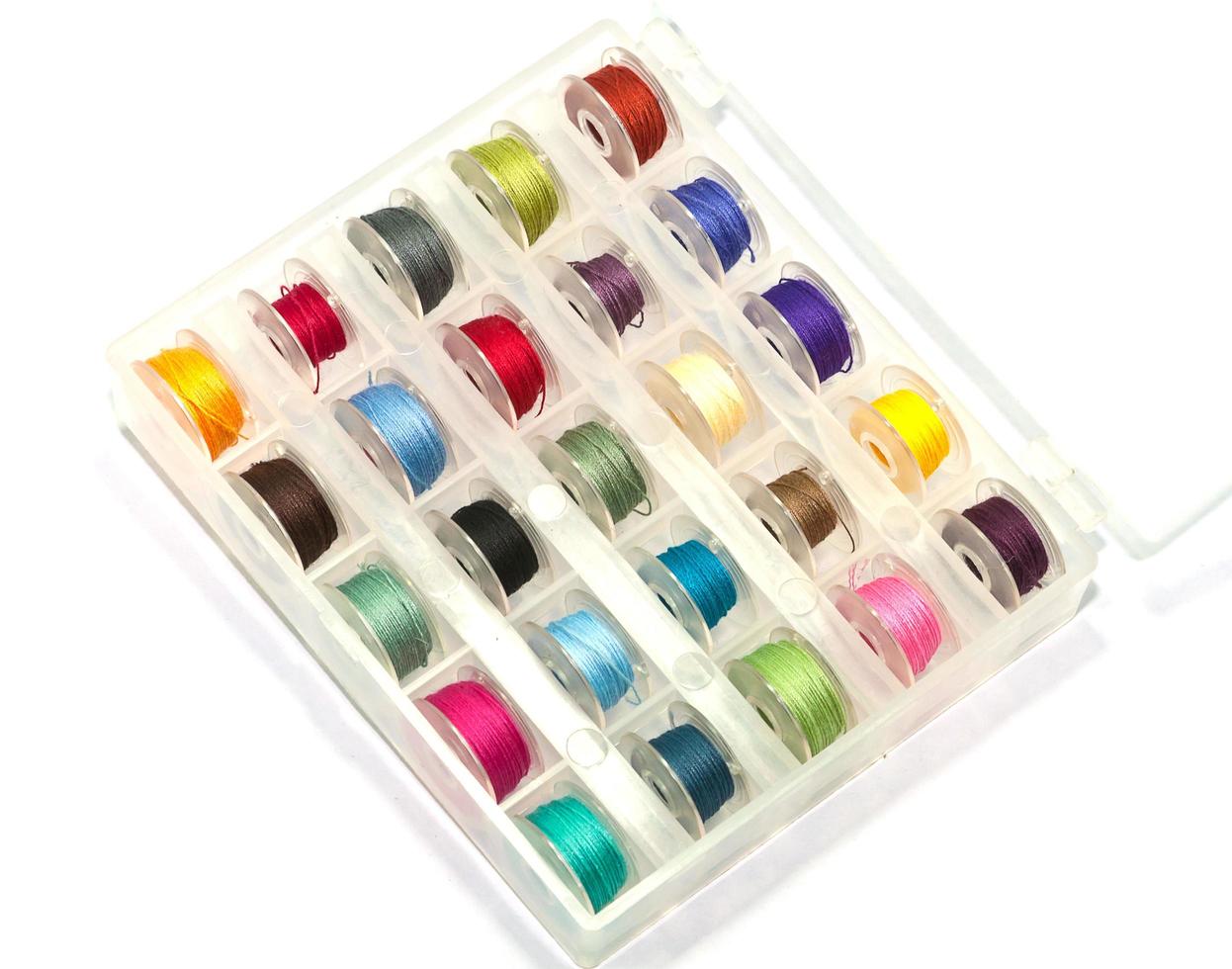 Box of colorful bobbins on white background photo