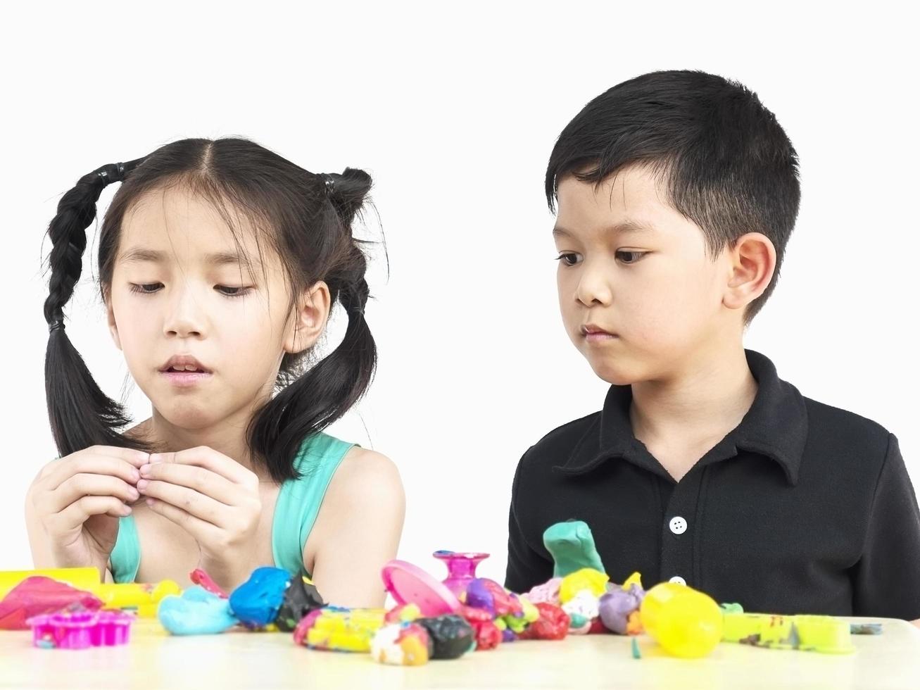 enfoque selectivo de niños asiáticos felices jugando juguetes de arcilla coloridos foto