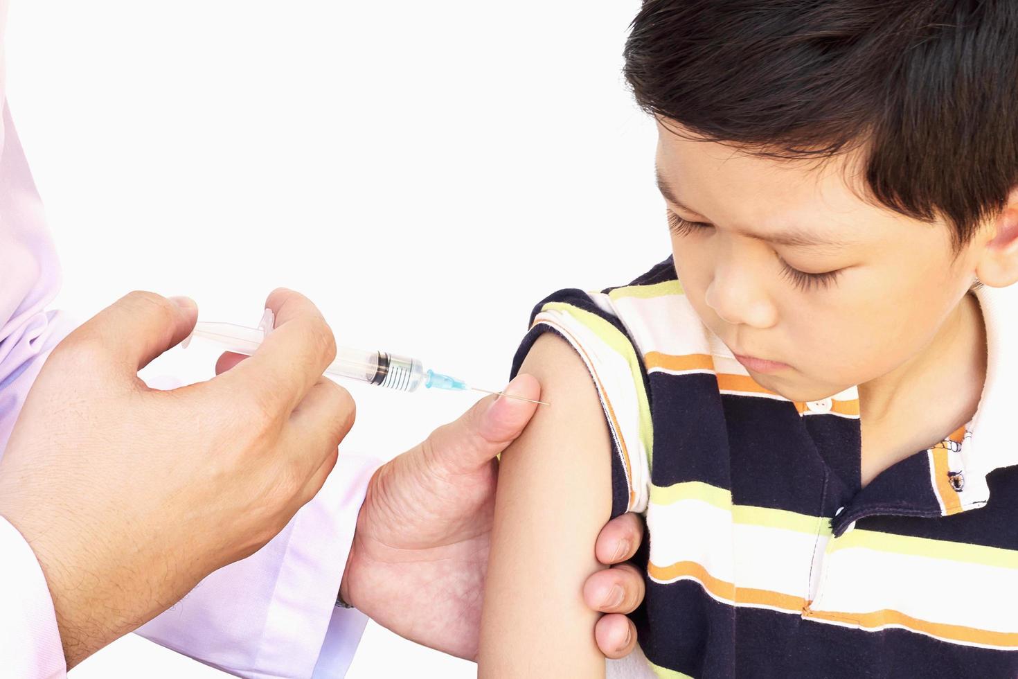 Sick Asian boy being treated by male doctor isolated over white background photo