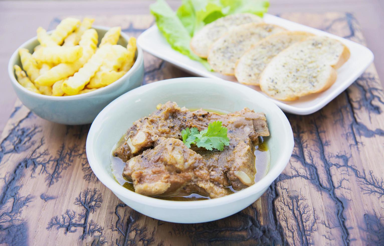 Pork stew serve with French fries and garlic bread photo