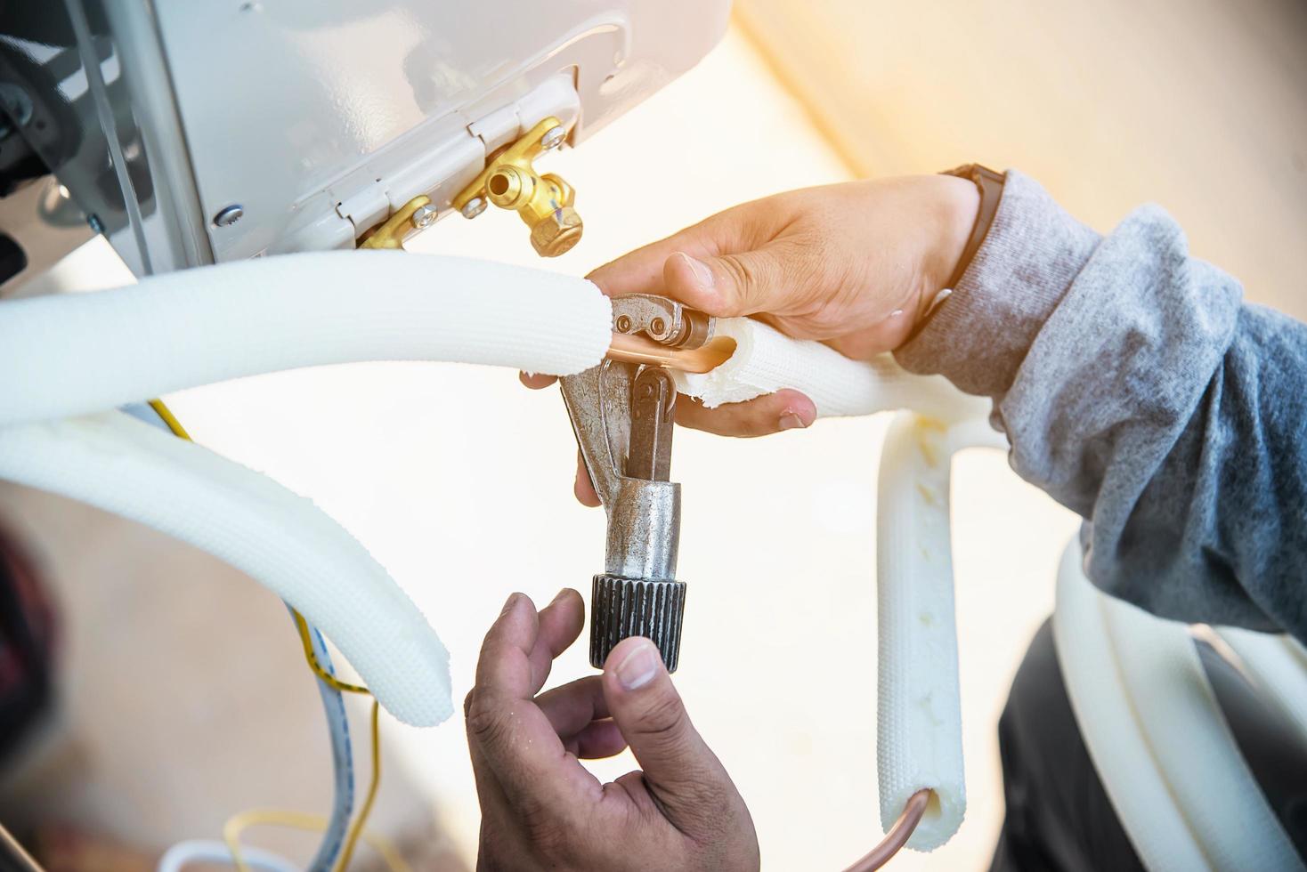 Man is installing wall compressor of air conditioner during hot season photo