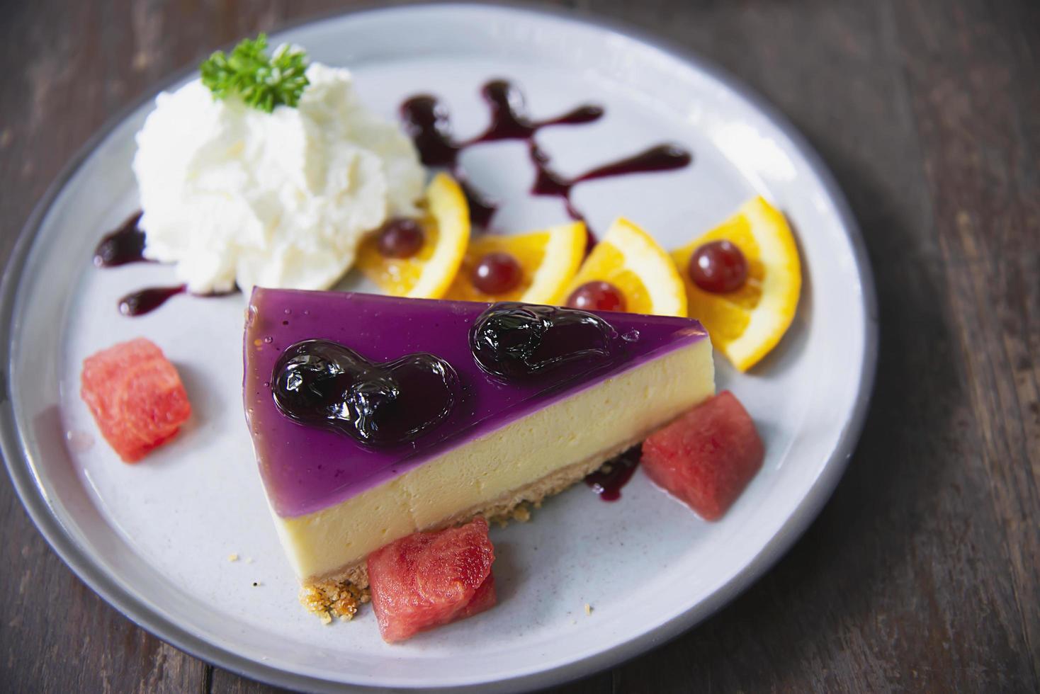 Colorful cheese cake blueberry favor with well decorated fruit pieces and whipped cream in white plate - cake recipe menu concept photo