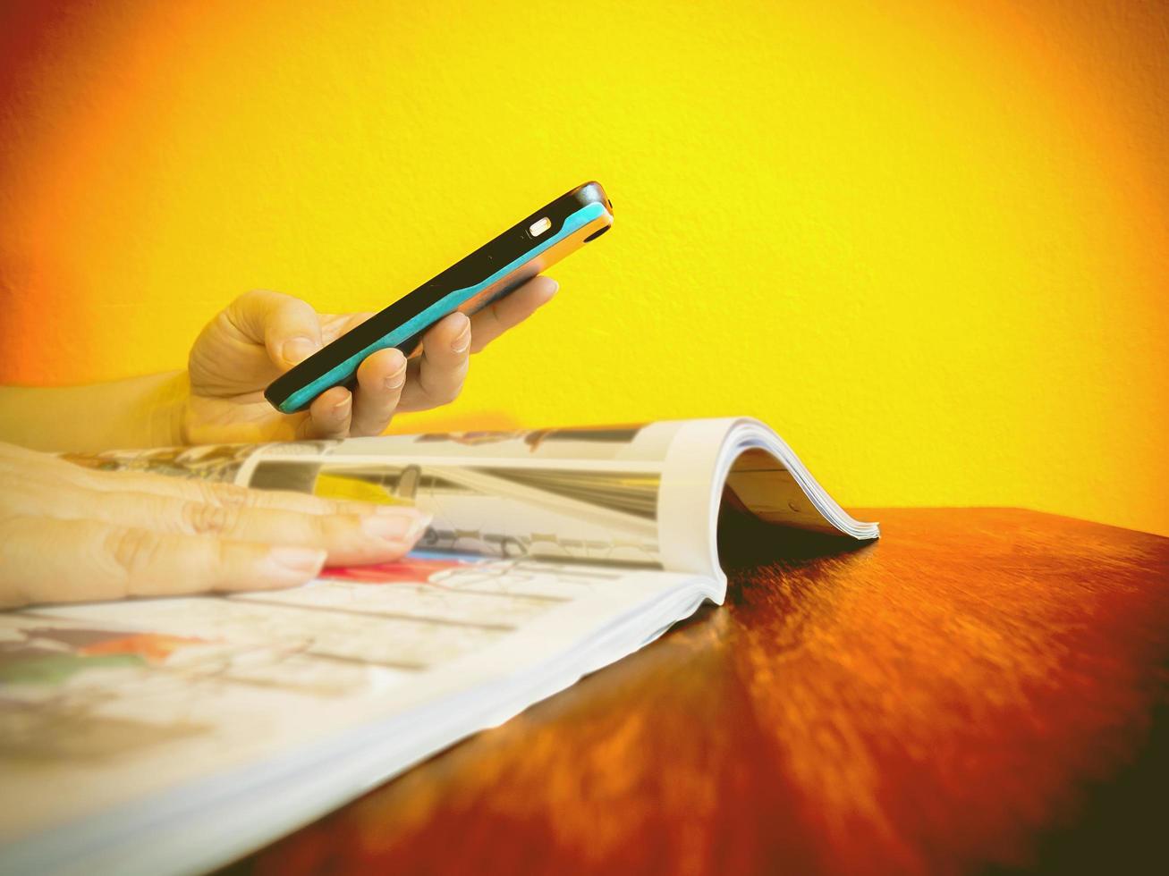 Someone is using telephone while reading a book catalogue to order something photo