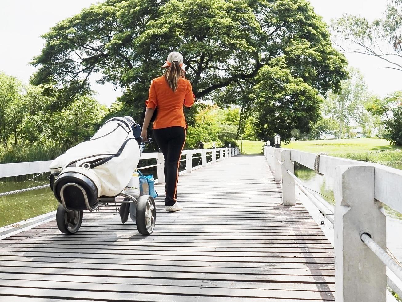 Golf caddy is walking with her trolley photo